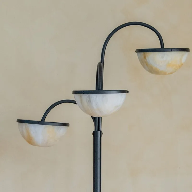 Close-up of three semi-sphere shades on a black triple-arm floor lamp