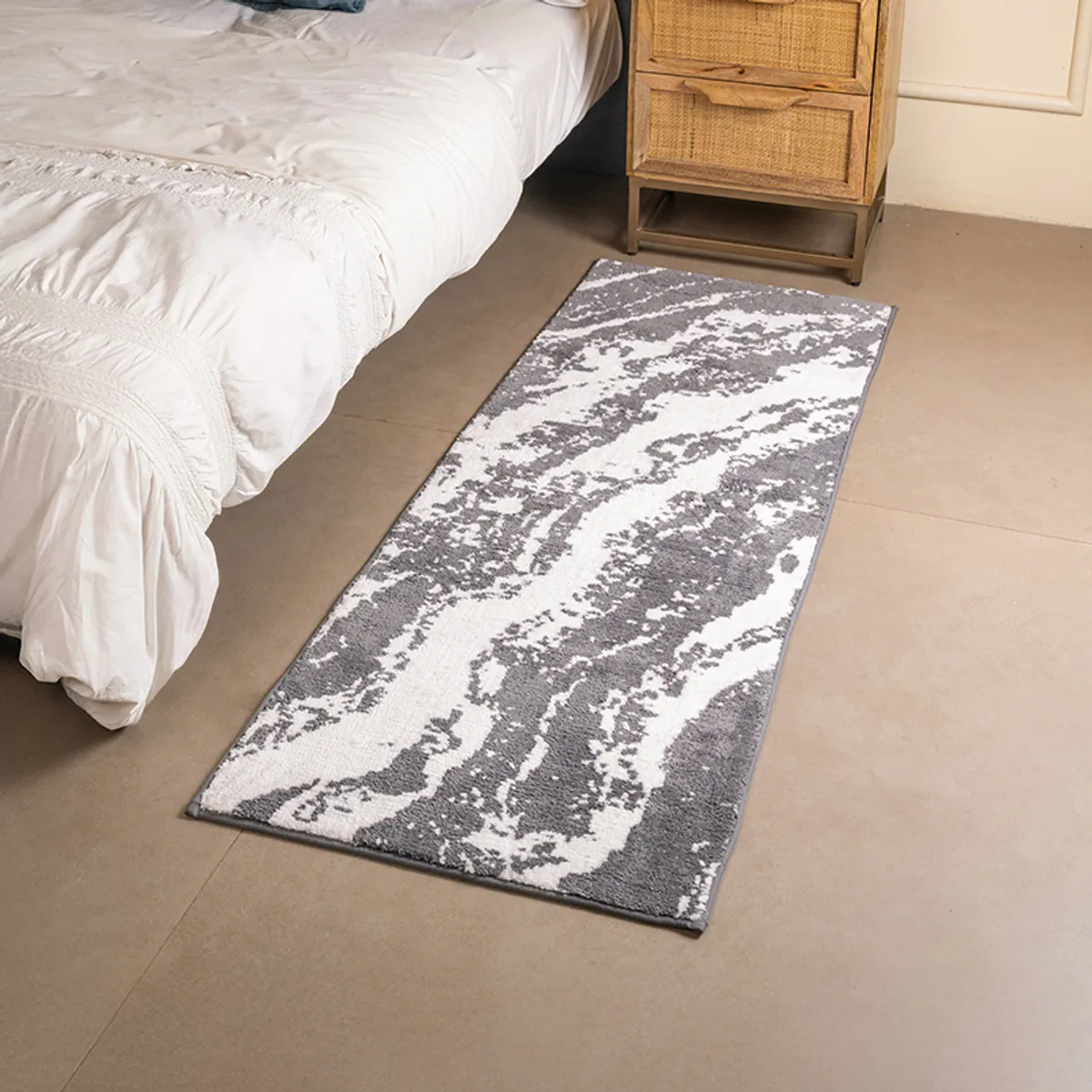 Grey and white marble-patterned runner rug placed beside a bed