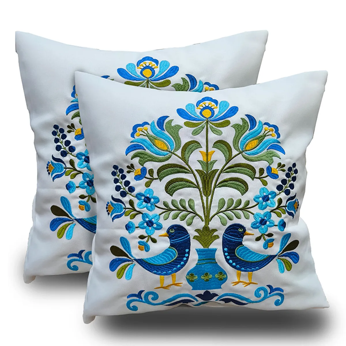 Two square cushion covers showing colourful blue bird and floral embroidery