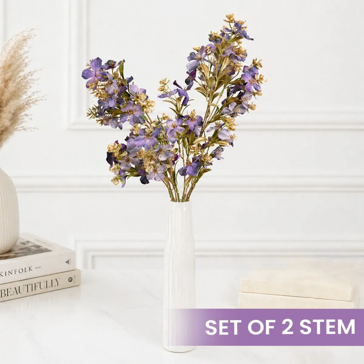 Set of purple and gold artificial flower stems arranged in a white vase