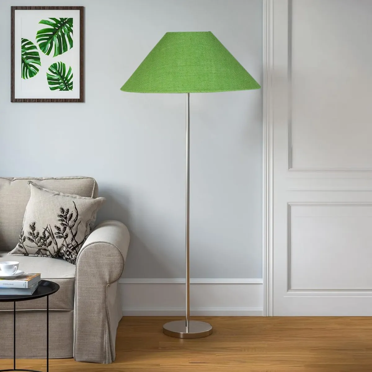 Green floor lamp against a pale wall beside a sofa and round side table