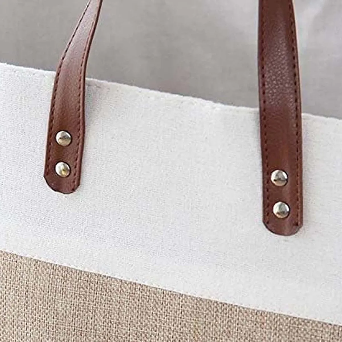 Close-up of the basket's brown carry handles on white fabric