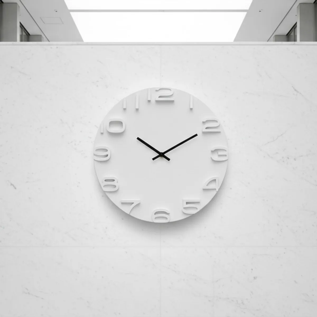 White round wall clock mounted on a bright marble-effect wall