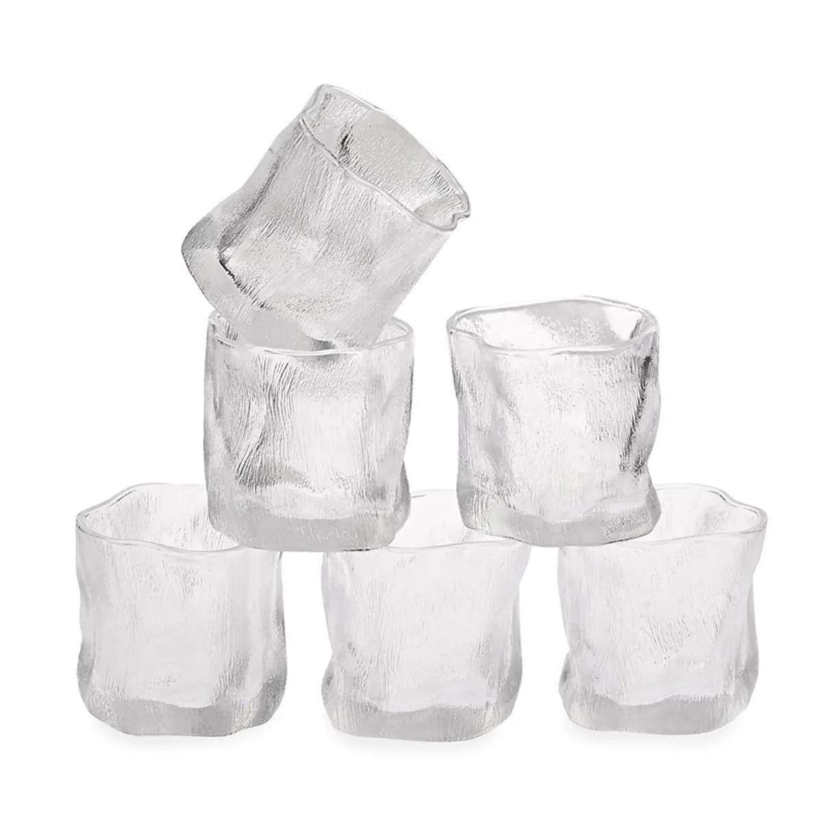Six clear textured whiskey glasses stacked against a plain background