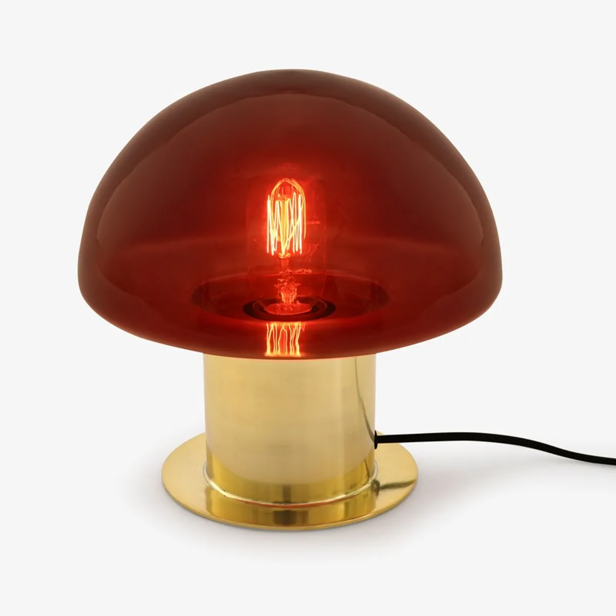 Red glass mushroom lamp illuminated, showing its gold base and black cord