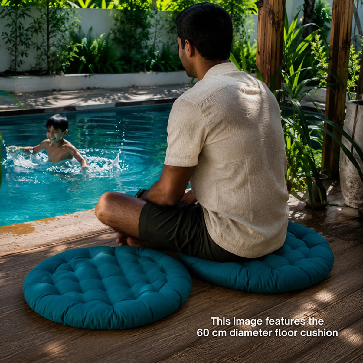 Round deep green floor cushions placed on a deck beside a swimming pool