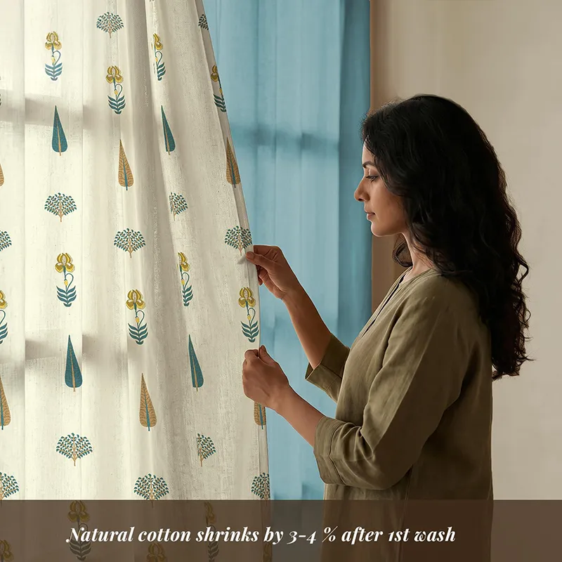 Woman holding a blue and white floral curtain panel near a solid blue curtain