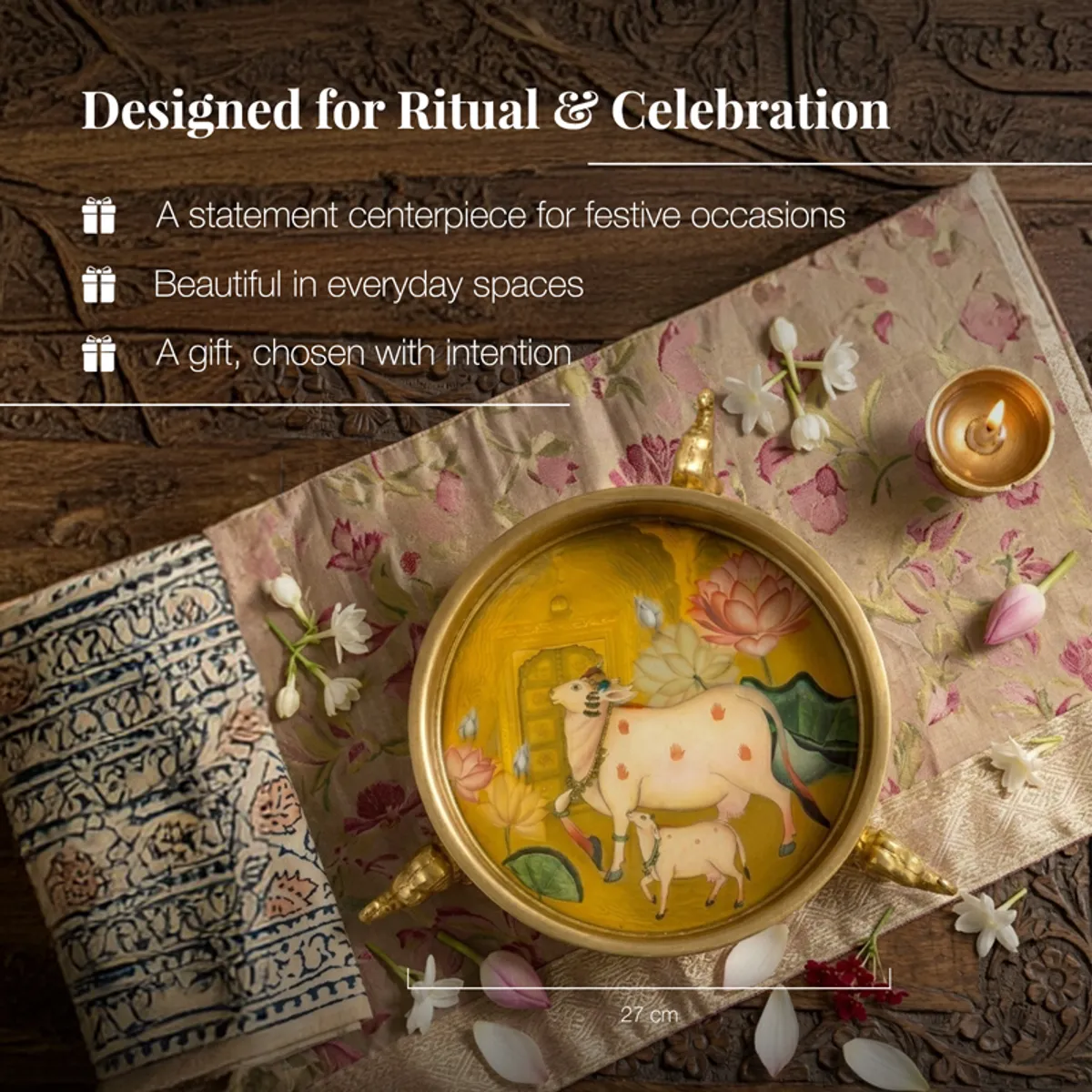 Gold Urli with colourful artwork styled on layered textiles with flowers