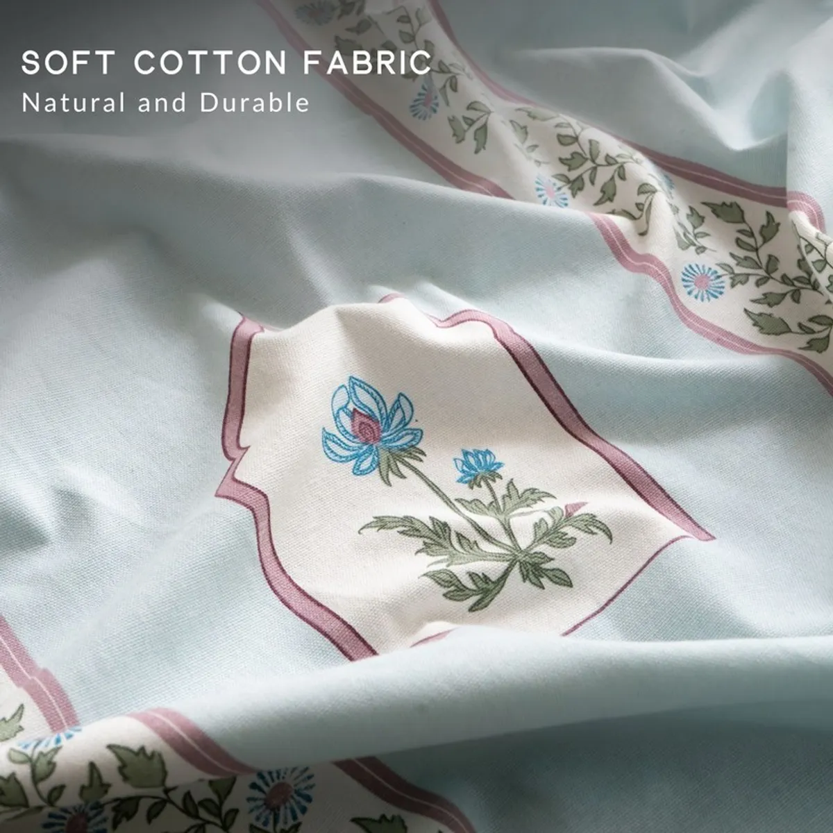 Close-up of soft cotton curtain fabric with floral borders and blue botanical motifs.