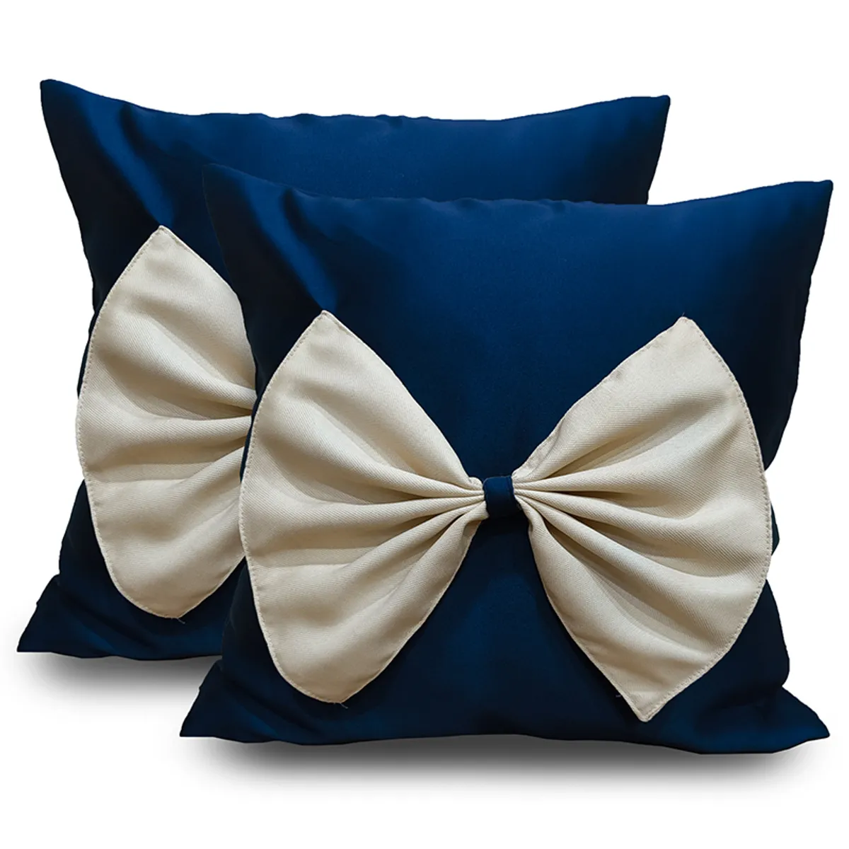 Two blue cushion covers with large cream bow details shown against a white background