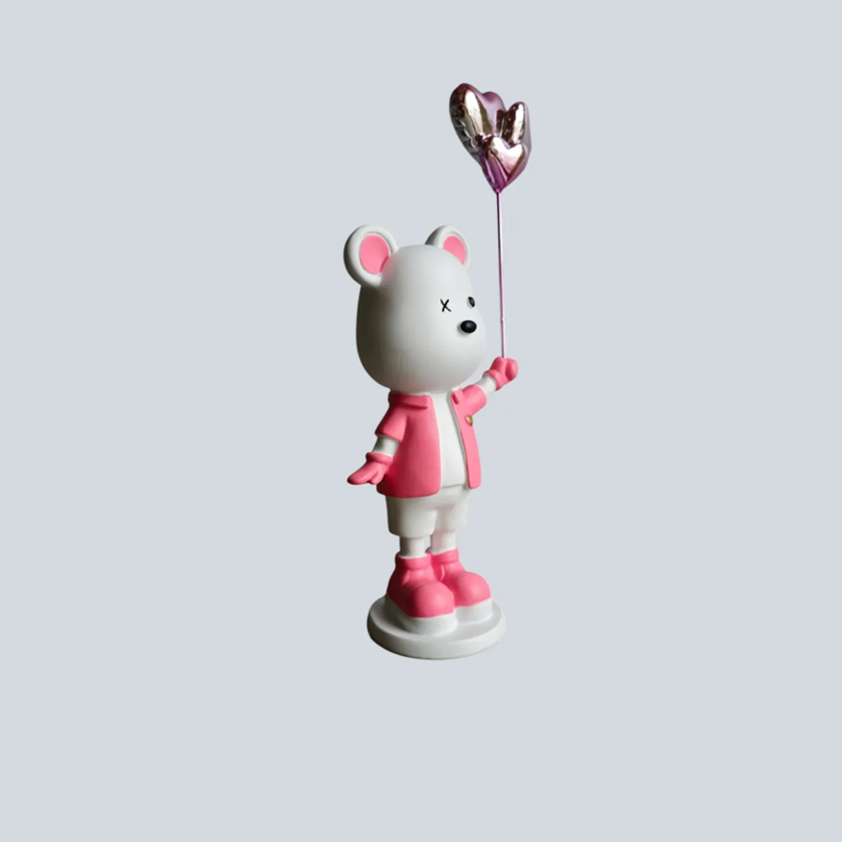 Side view of the pink and white bear figurine holding a heart balloon