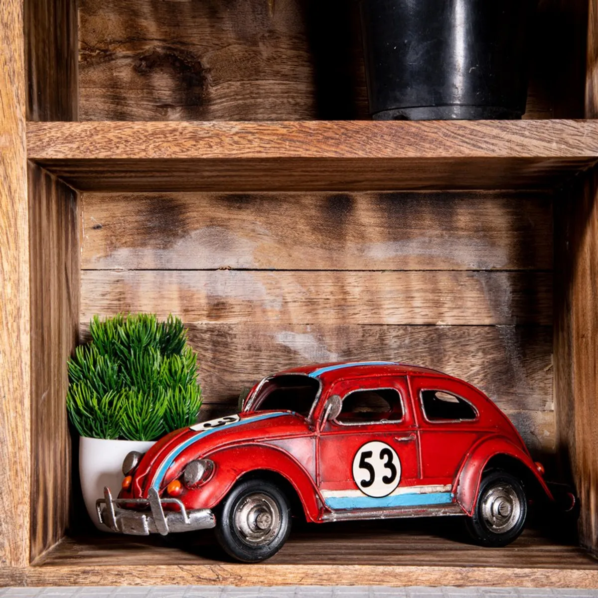Red vintage car tabletop showpiece styled on a wooden shelf