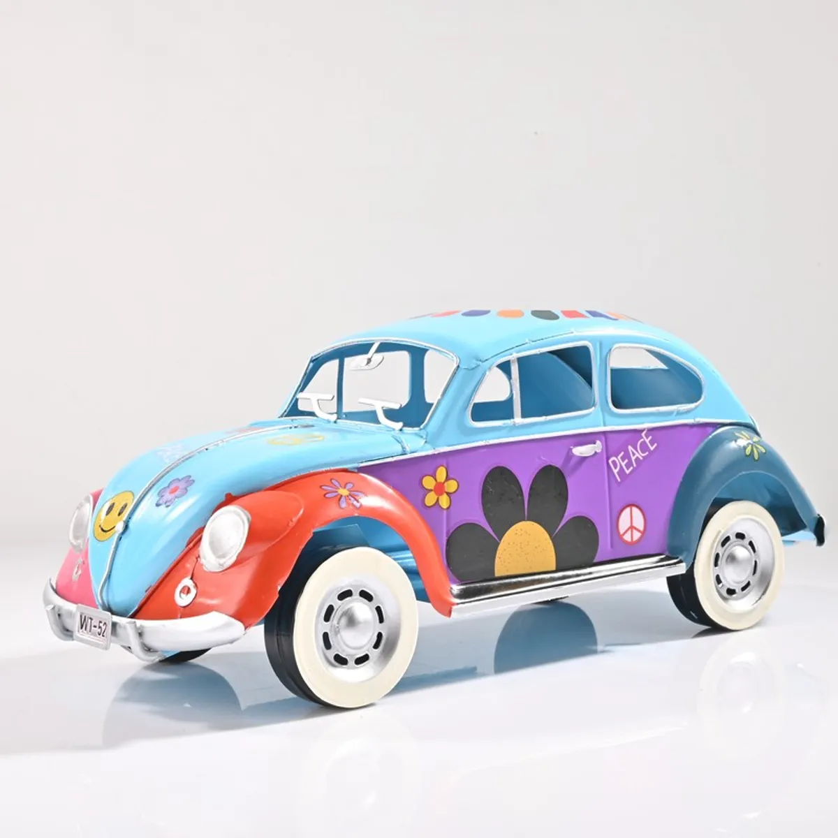 Front angled view of blue vintage car showpiece with floral and peace motifs