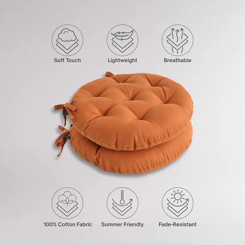 Two stacked round brown chair pads with tufted surface and ties