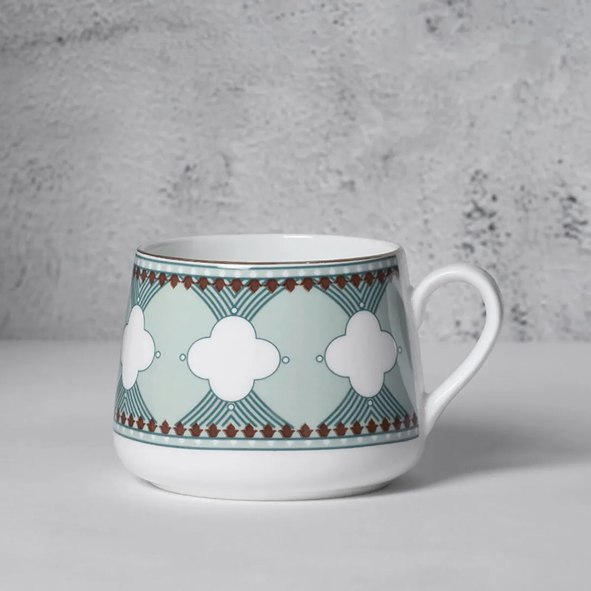 Single teal and white patterned cup shown against a grey textured backdrop