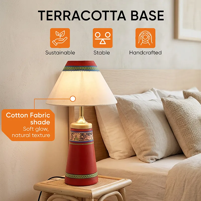 Red terracotta table lamp with cream shade styled on a small stool by a bed