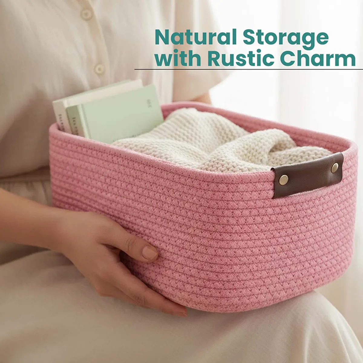 Person holding a pink woven storage basket filled with a knitted throw and books
