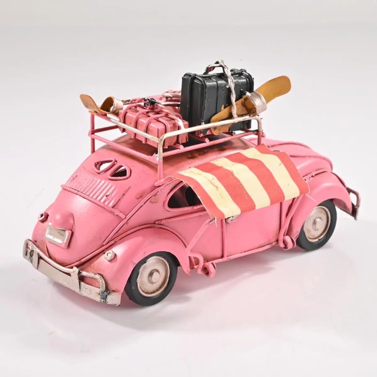Rear view of pink vintage beetle car showpiece with rooftop luggage