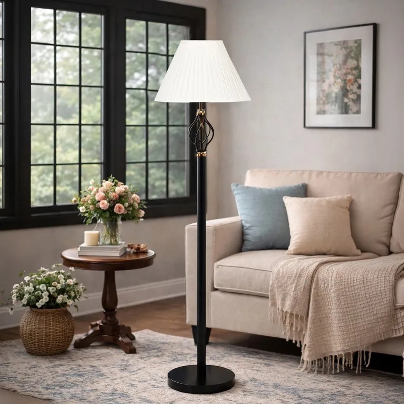 Black floor lamp with white pleated shade in a bright living room beside a sofa