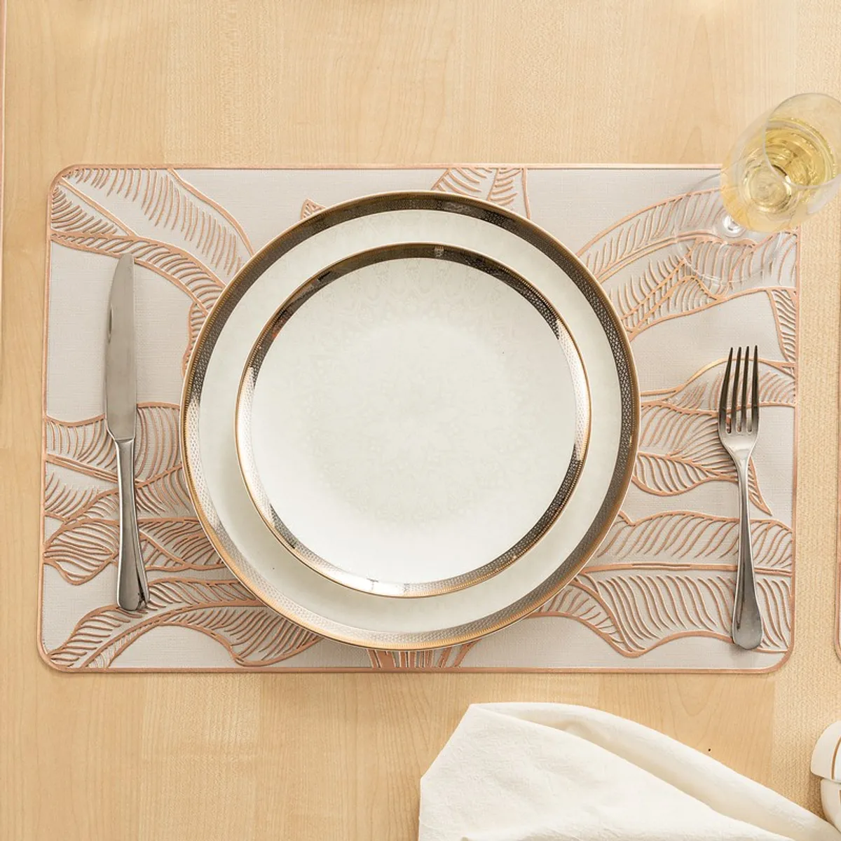Single rectangular gold placemat styled with plate, cutlery and glass