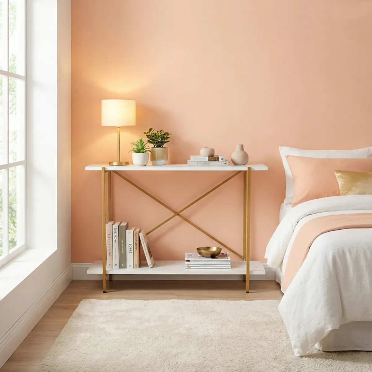 White and gold console table styled with plants and books beside a bed