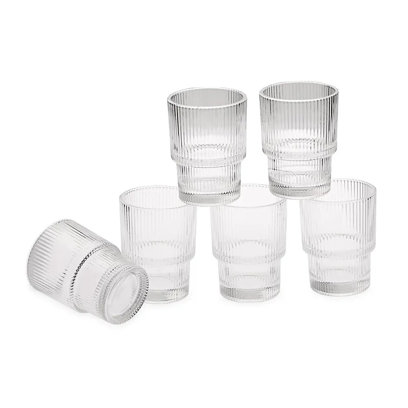 Six clear ribbed cocktail glasses arranged on a white background
