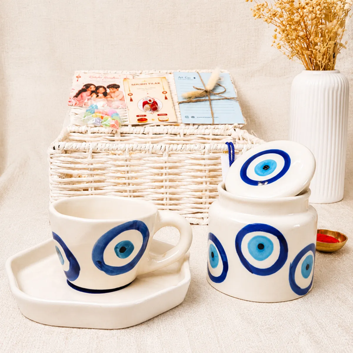White evil eye mug and matching jar arranged with a woven hamper basket