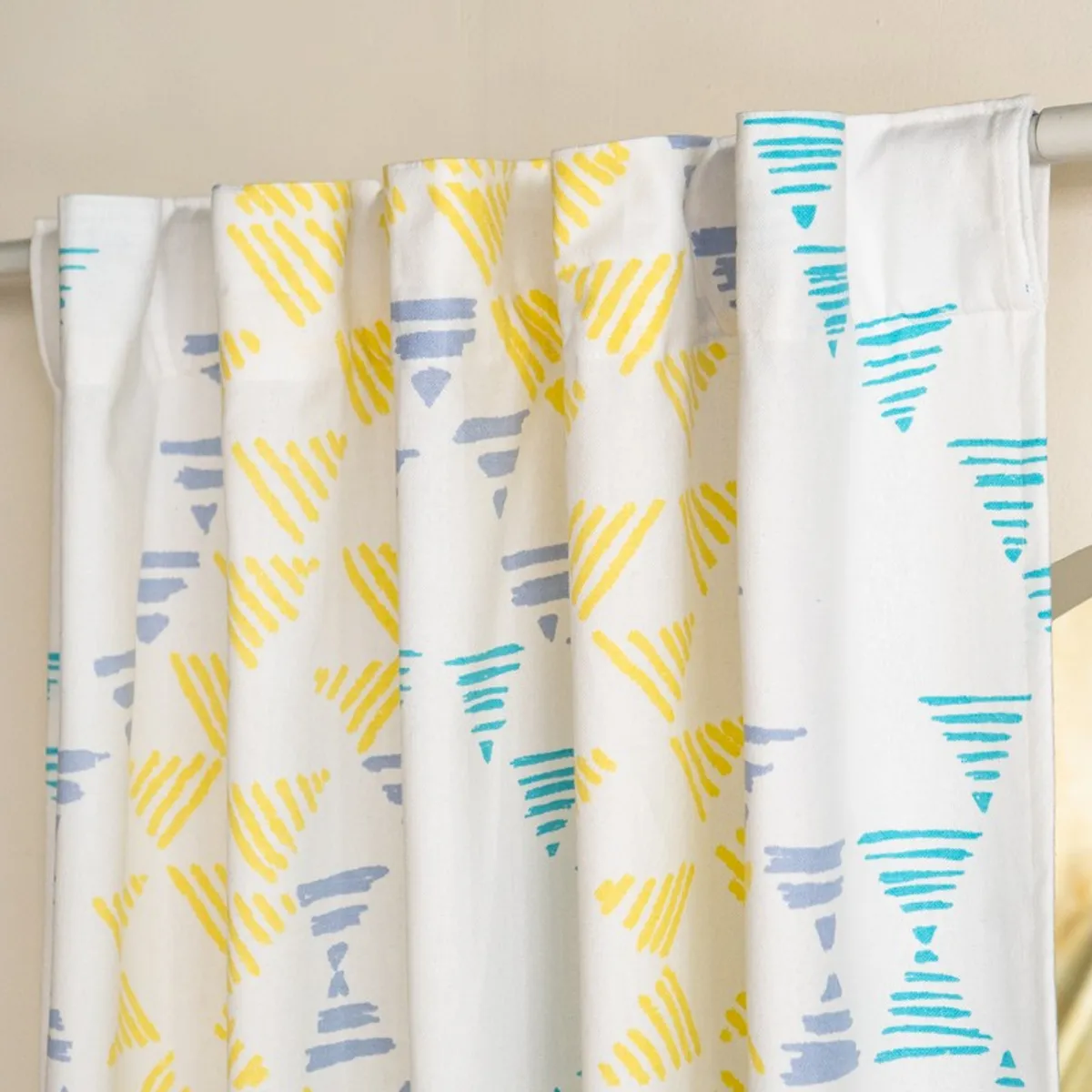 Close view of back-tab curtain top with colourful geometric print