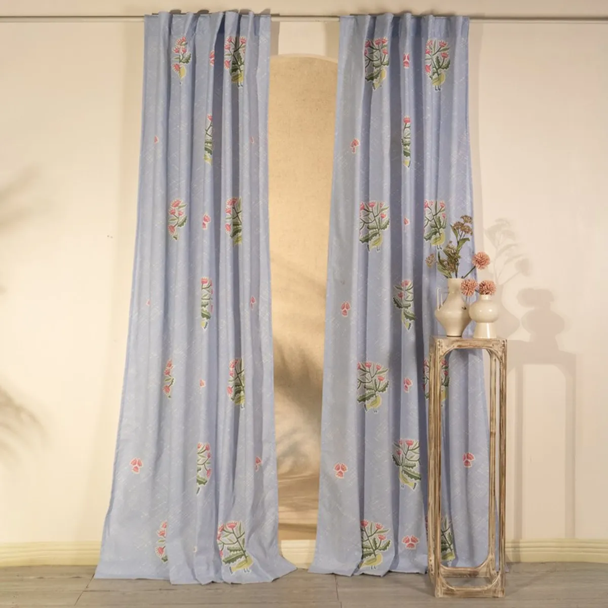 Pair of light blue floral curtains framing a doorway and console