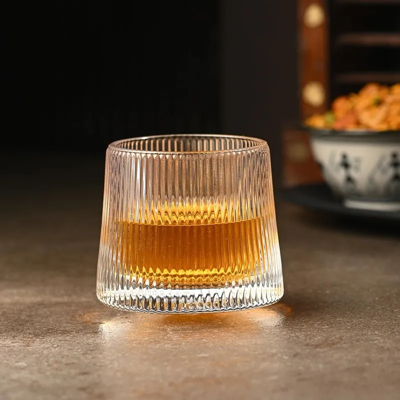 Single clear ribbed whiskey glass filled with amber drink