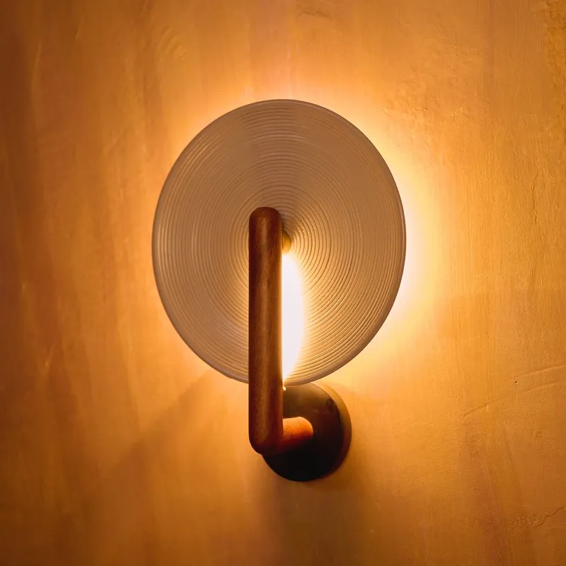 Front view of illuminated wood wall lamp with circular ridged shade