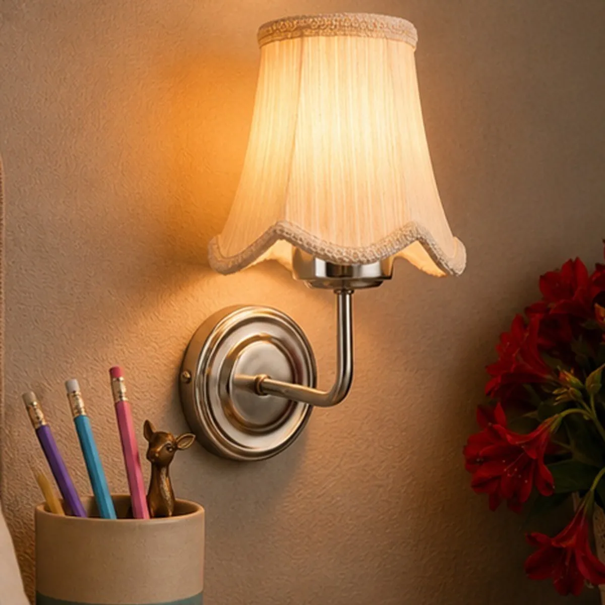 Lit white cotton wall lamp with a polished steel base on a light-coloured wall