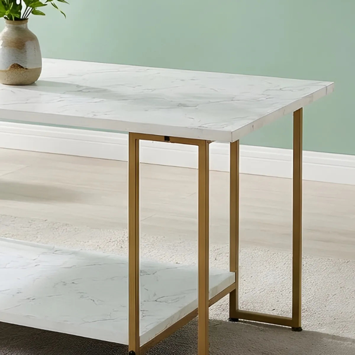 Close view of the white tabletop, lower shelf and slender gold-toned metal frame