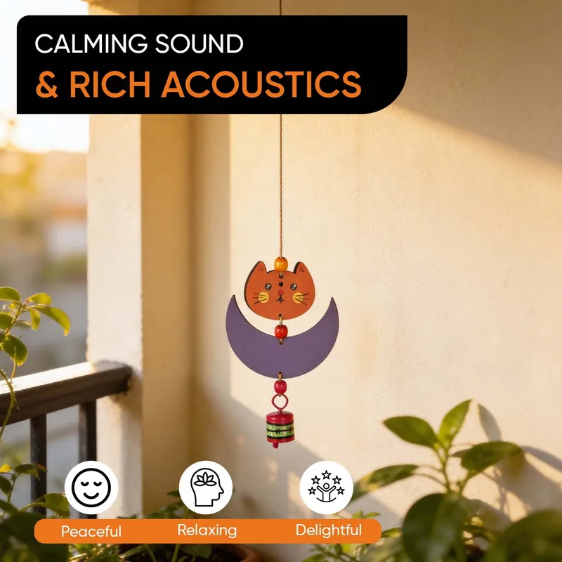 Cat-and-moon windchime hanging near plants with a visible decorative bell.