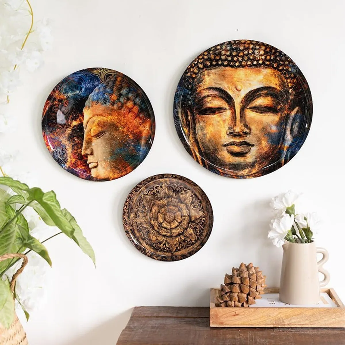 Three multicolour Buddha wall plates displayed on a white wall.