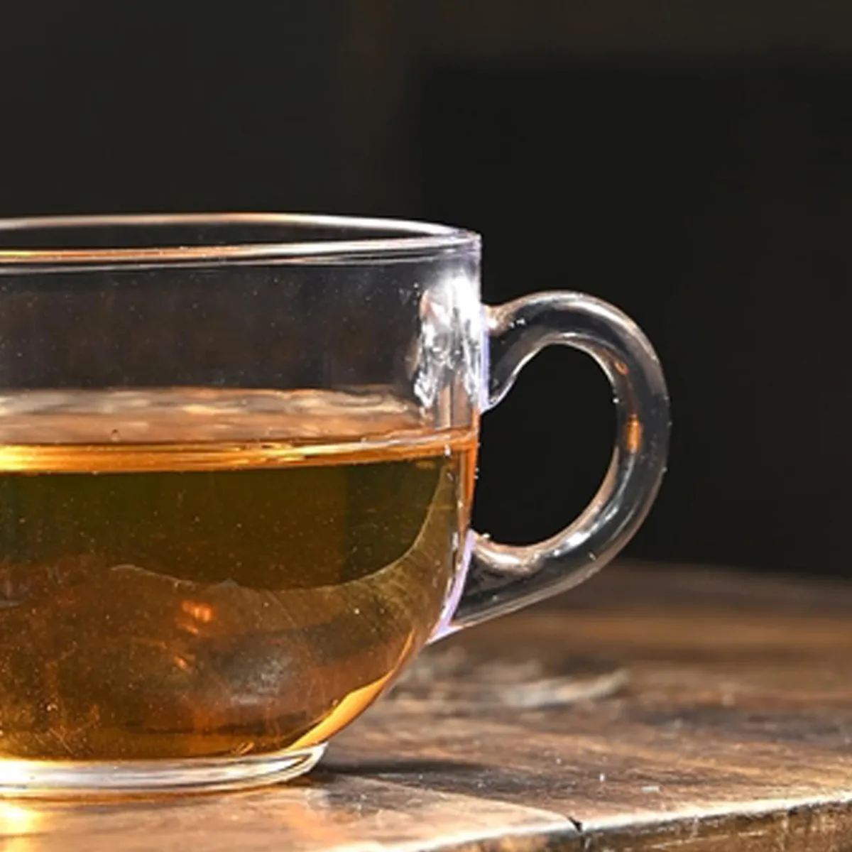 Close-up of transparent glass tea cup filled with amber tea