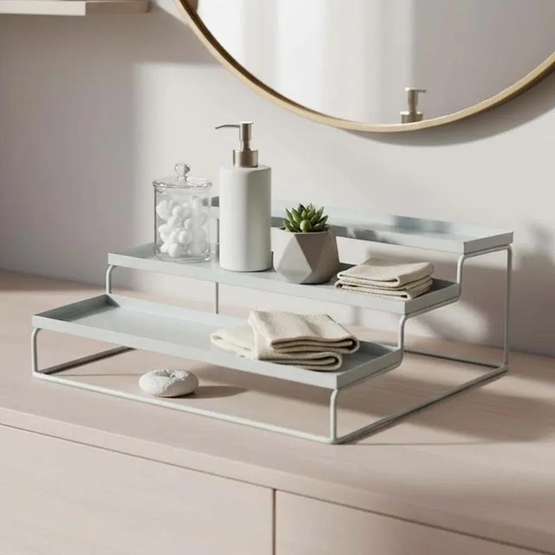 White metal tiered organiser on a bathroom counter with towels, bottle and jar