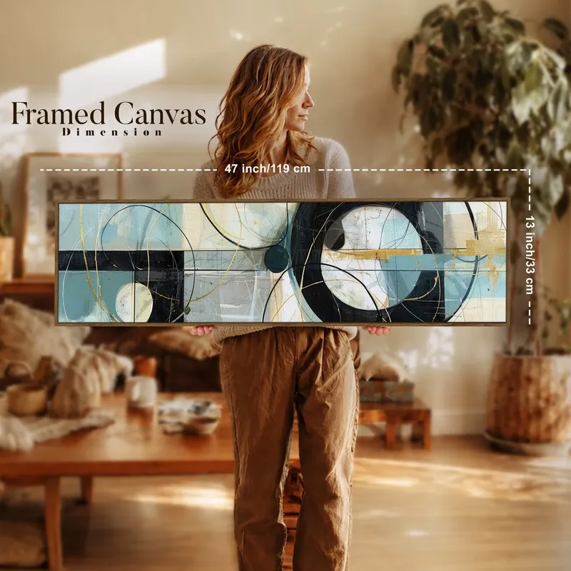 Person holding a long framed abstract canvas in blue, black and gold indoors