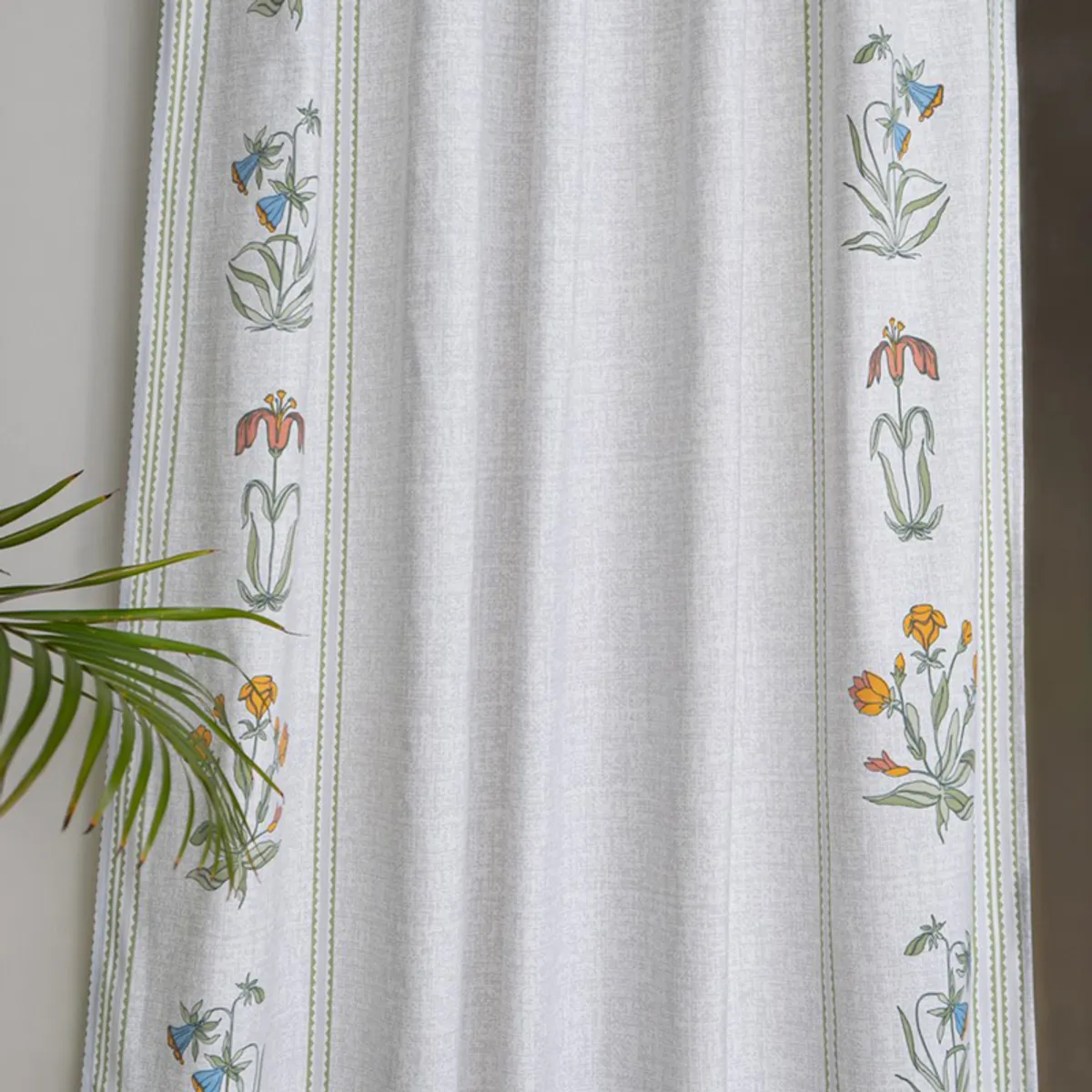 White curtain with colourful botanical motifs and green striped borders