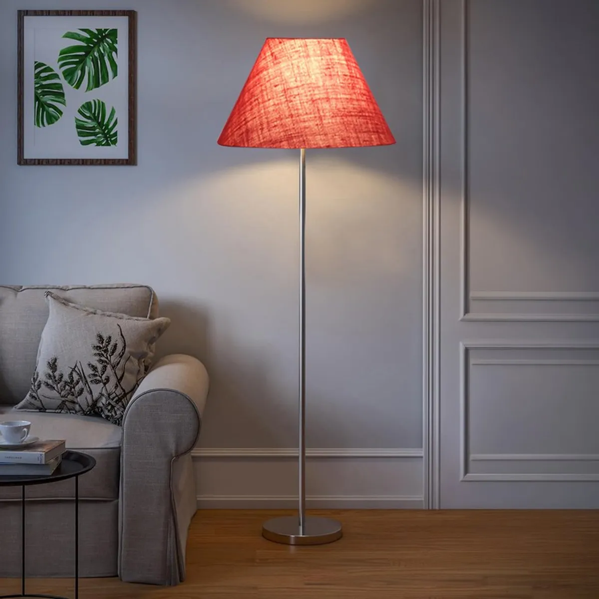 Lit rose blush floor lamp with conical shade beside a sofa