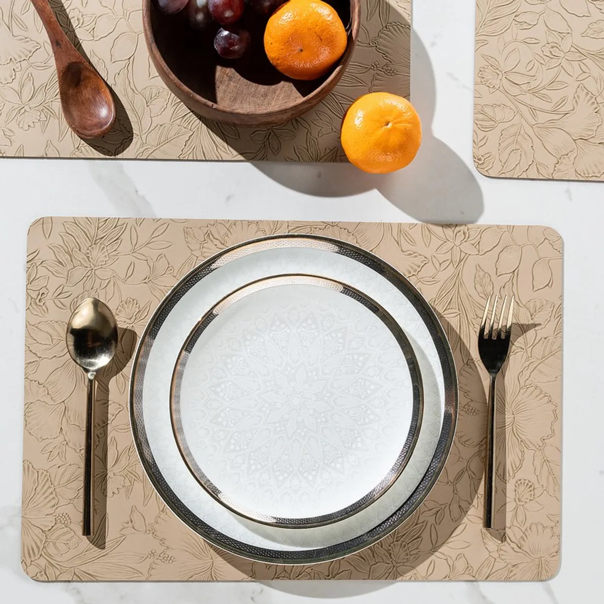 Top view of beige floral table mat with plate, spoon and fork