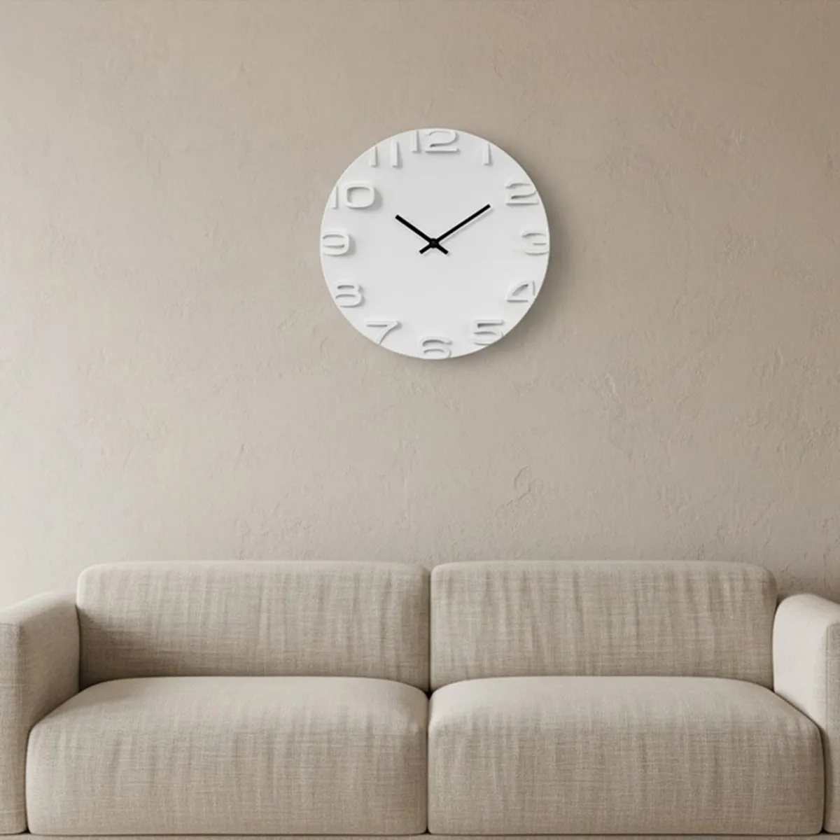 White wall clock displayed above a neutral sofa against a textured wall