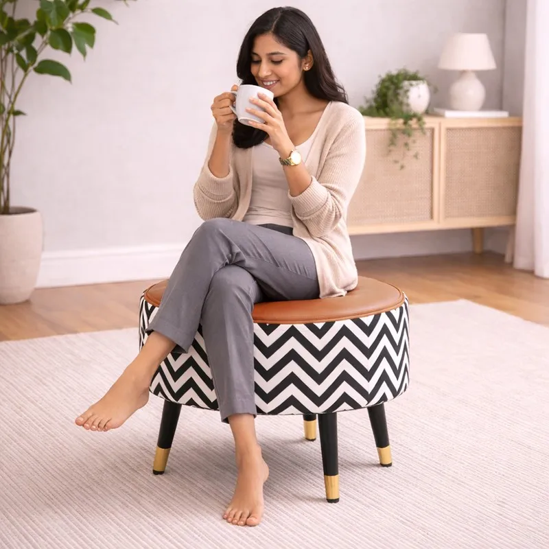 Person seated on a round brown and grey chevron ottoman