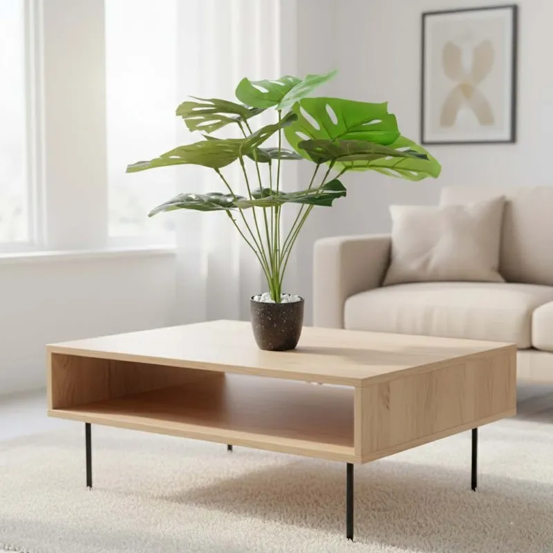 Artificial Monstera plant in a black pot on a modern coffee table.