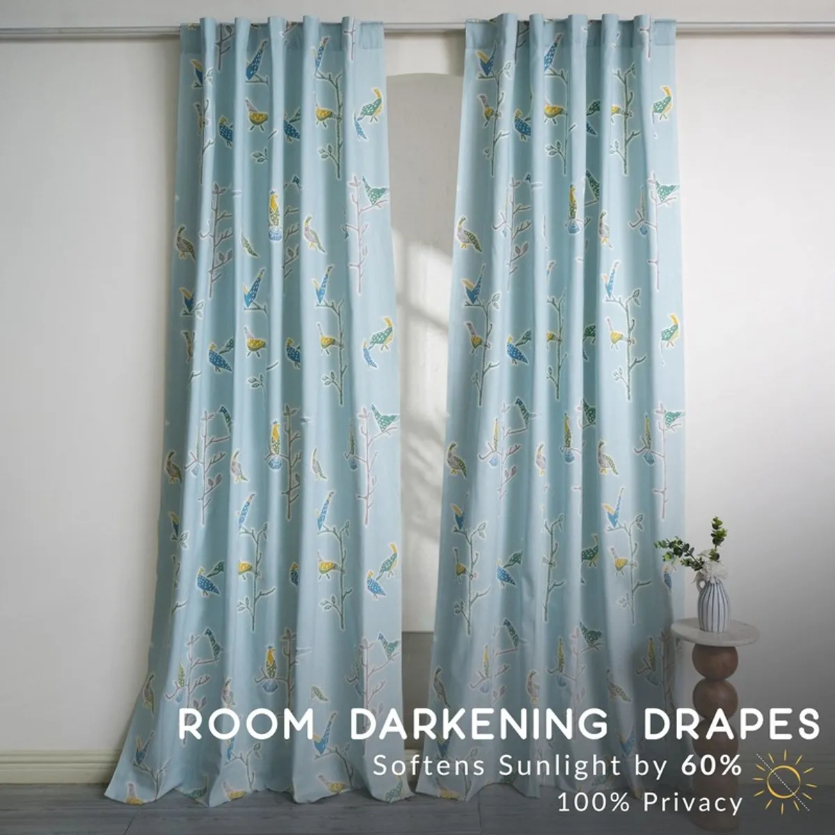 Two blue printed curtains hanging from a rod in a bright room