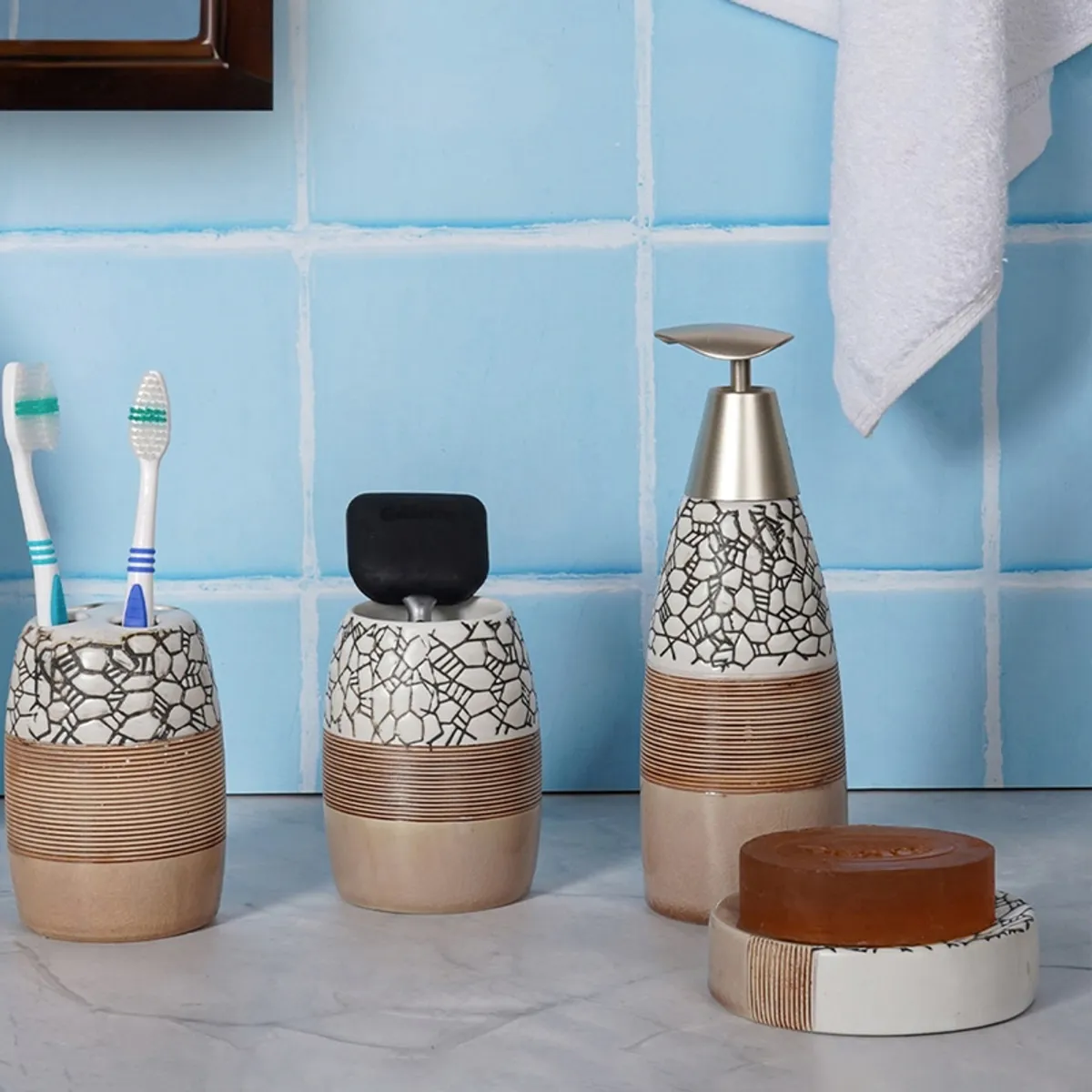 Beige ceramic bathroom set arranged against blue tiles, including dispenser, tumbler, holder and dish