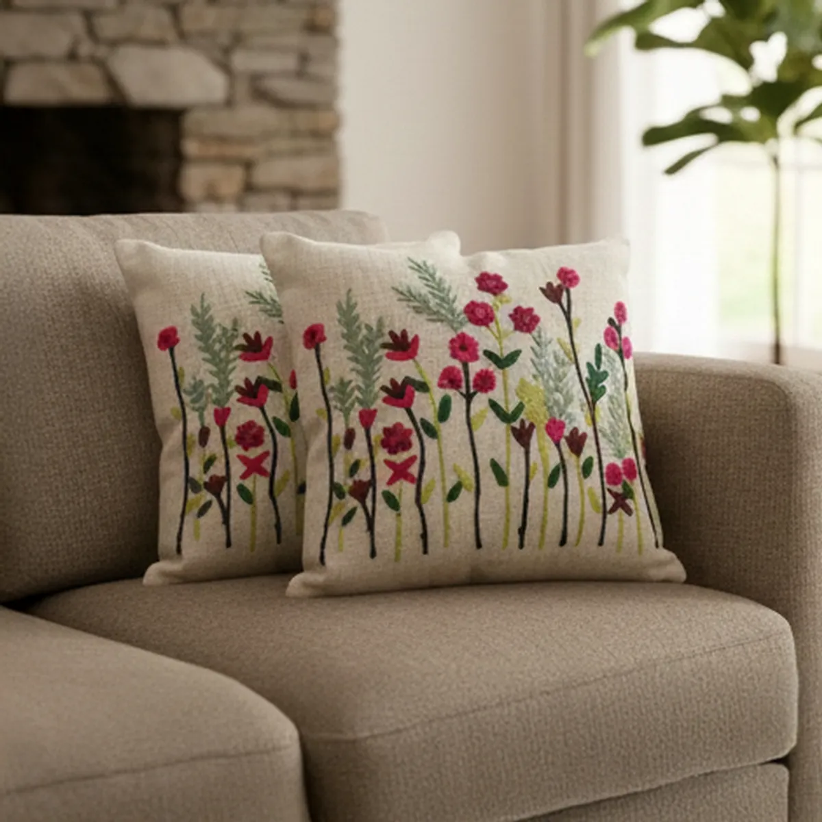 Two embroidered floral cushion covers styled on a neutral sofa.