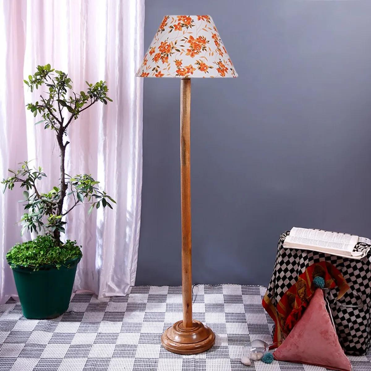 Tall wooden floor lamp with orange floral shade against a grey wall