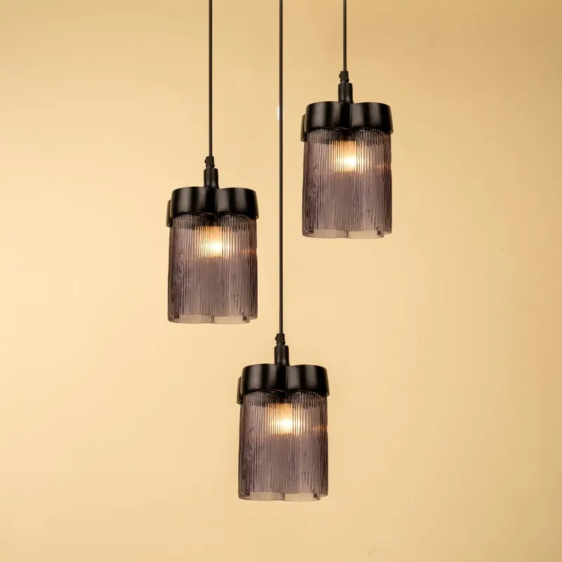 Three illuminated smoky glass pendant lamps suspended at different heights