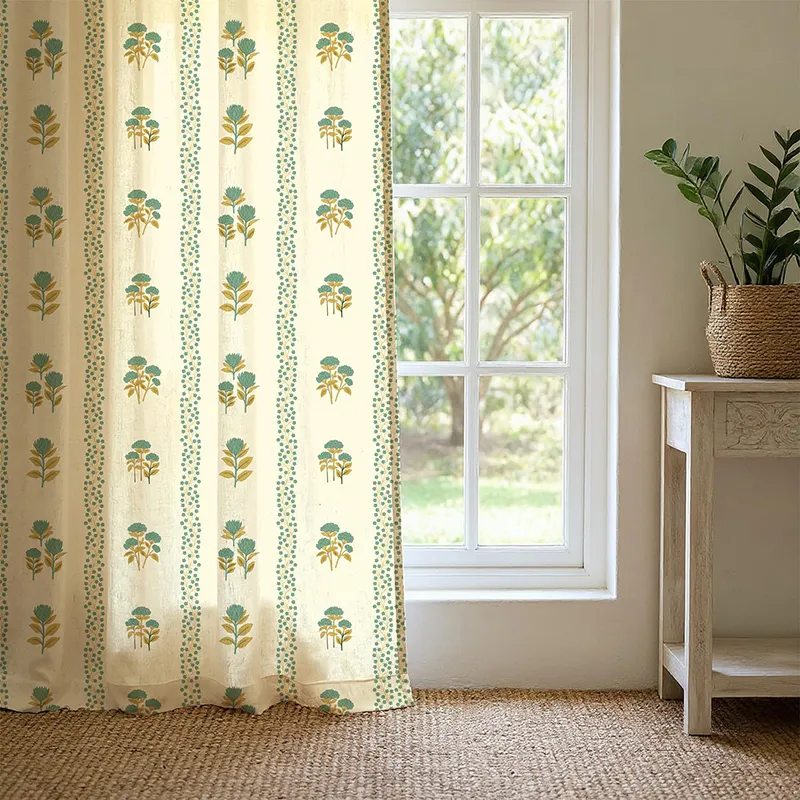 Sage green floral printed curtain beside a bright window